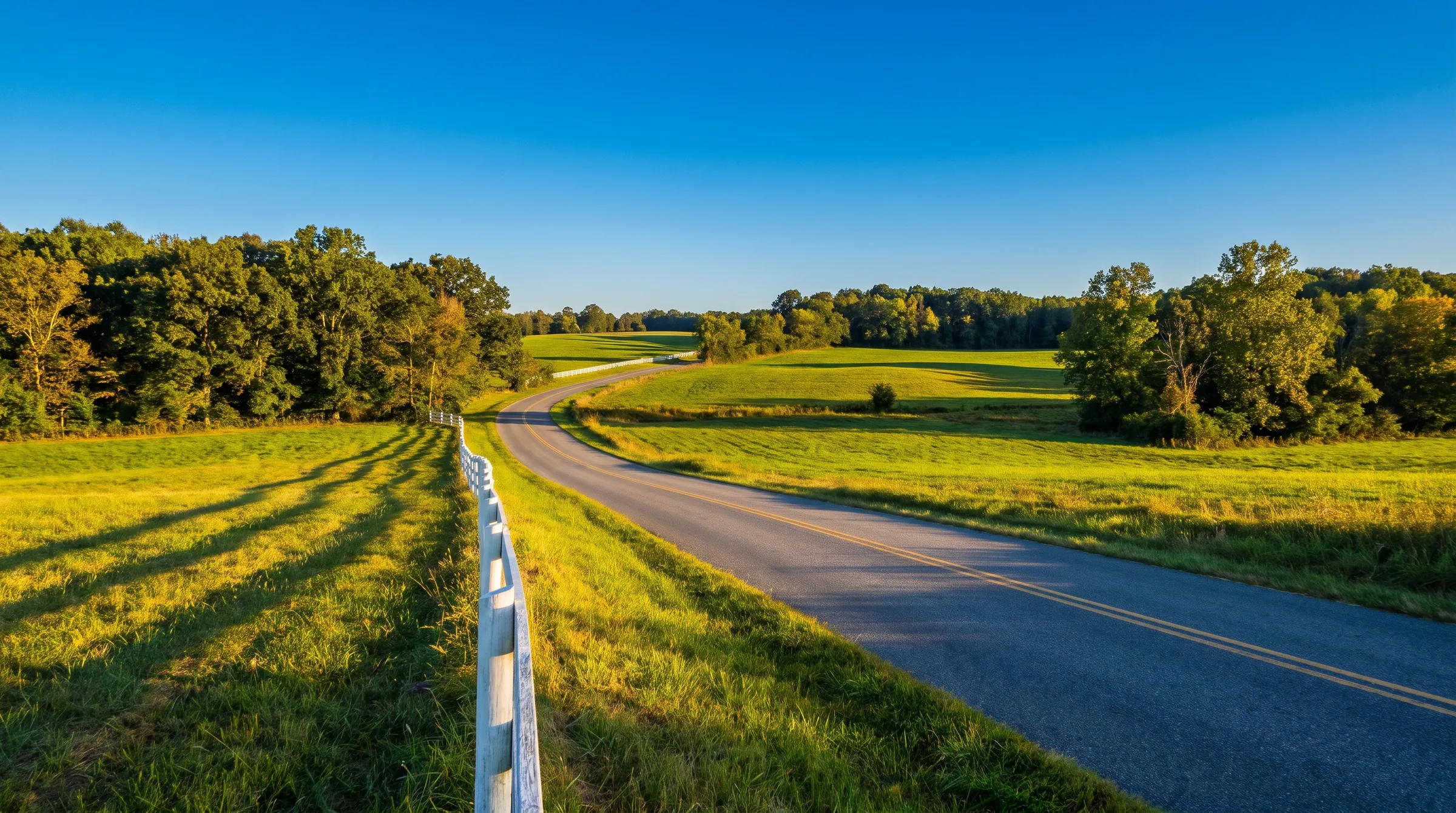 Country road between green fields and woods in late-afternoon light near Brandywine, Maryland